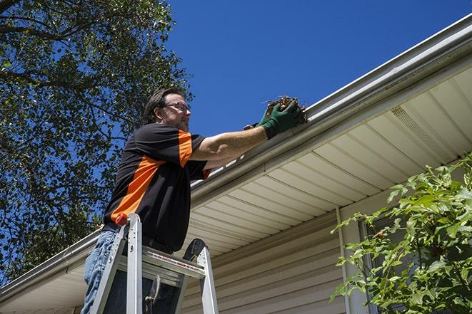 worker repairing a leak in a residential gutter in Bingham Farms MI